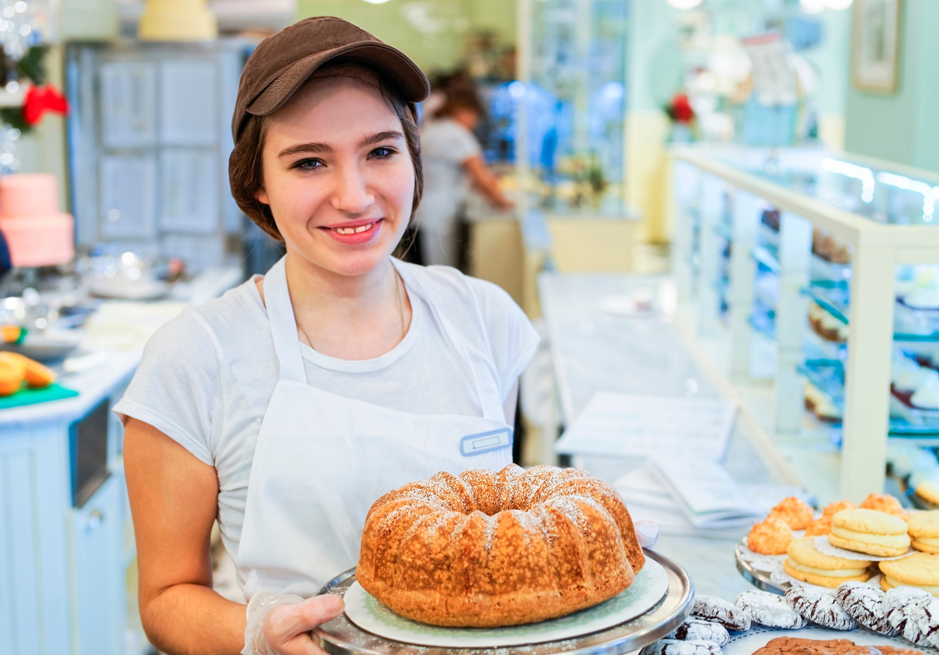 Souriant belle fille avec un gâteau à la boulangerie